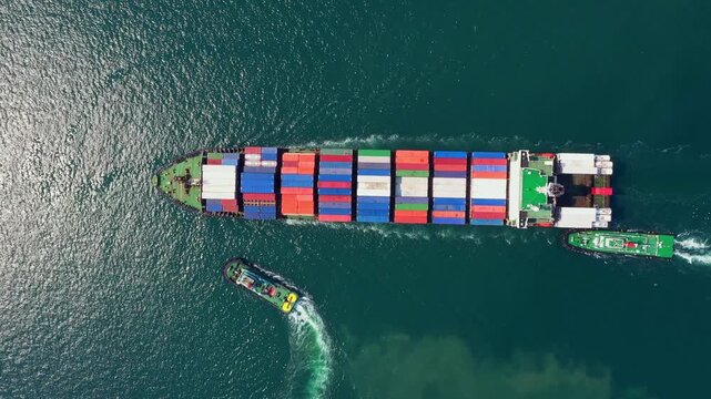 Large container ship navigates through dark ocean waters with escort tugboats assisting its passage to Port, delivering vital cargo amidst challenging maritime conditions.