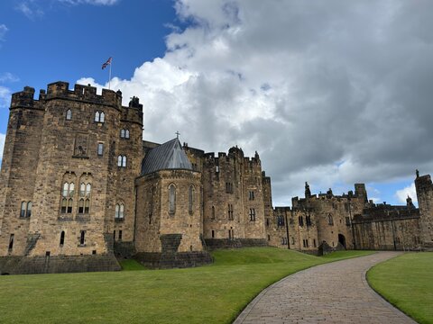 Medieval Fortress Grounds: Lush lawn and arched path directing toward a centuries-old castle