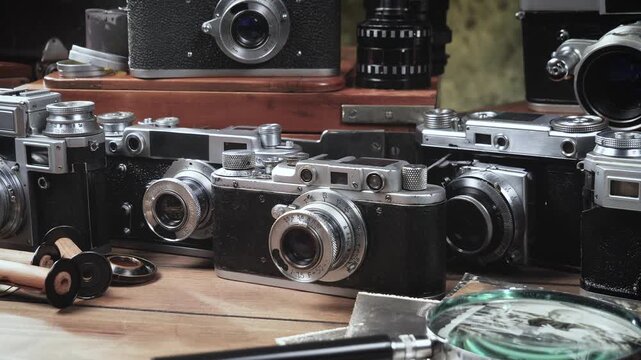 Old cameras in a composition on a wooden background, slowly moving in a horizontal plane.
