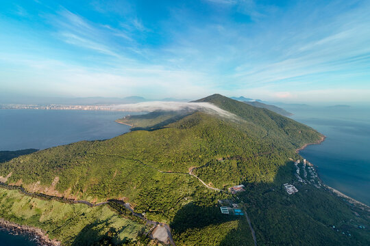 Green mountains of Son Tra Peninsula rise above the calm blue sea of Danang in Vietnam under a bright sunny sky during a peaceful morning in the forest