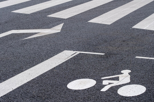 A white bicycle lane symbol and arrow create a precise road marking, separating cycling direction from traffic movement within the urban streetscape