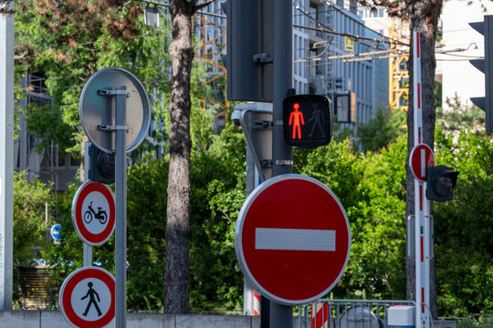 Prohibition signs restrict entry for bicycles and pedestrians beside a red signal, concentrating urban traffic rules and safety at the intersection