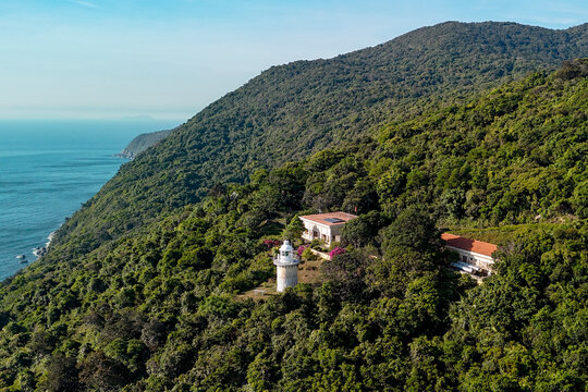 Coastal lighthouse perched on the lush green hills of Son Tra Peninsula overlooking the deep blue sea near Danang on a sunny afternoon with clear skies