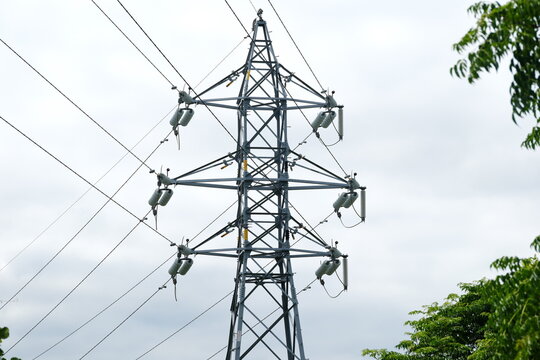 Electricity pylon transmitting power lines against cloudy sky