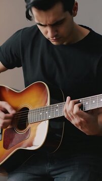 Vertical video: Playing man practicing chords as right hand moves at home acoustic guitar black tee