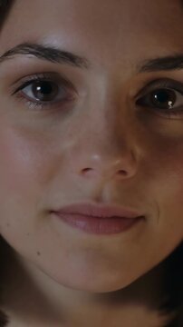Vertical video: Speaking adult female saying brief line returning smile in studio, camera recording
