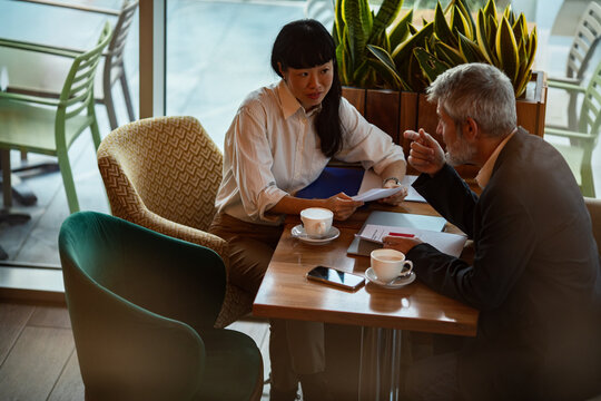 Colleagues discussing documents over coffee in a cafe