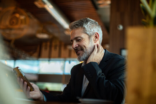 Smiling businessman checking smartphone in cafe