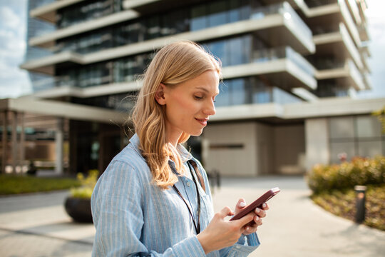Young woman using smartphone outside modern office building