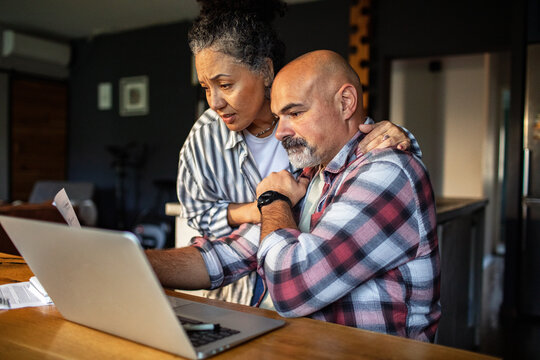 Mature couple managing finances on laptop at home