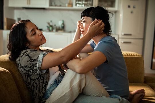 Two women share comforting moment on cozy sofa at home