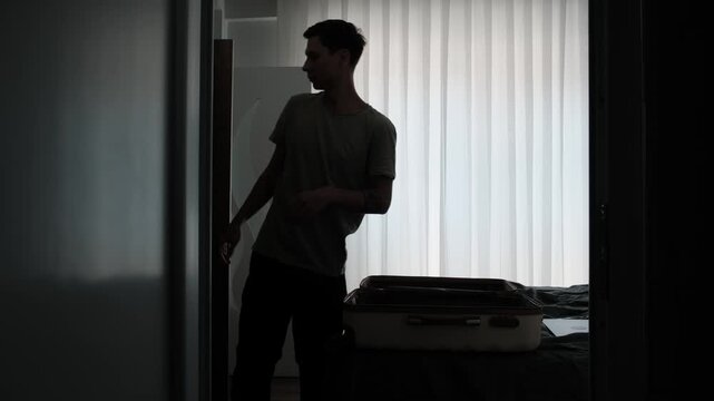 Life transition and constant relocation. Man packing suitcase in temporary home while preparing for another move, authentic modern lifestyle during uncertain times