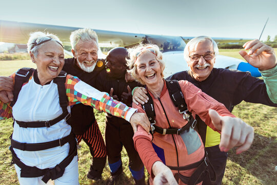 Happy senior friends in skydiving gear at airfield