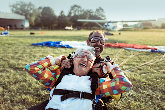Senior woman and instructor after tandem skydive landing on airfield