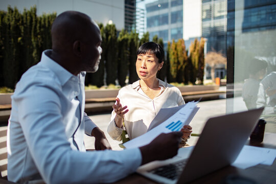 Coworkers discussing financial report in office courtyard
