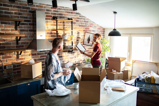 Two men unpacking boxes in modern loft kitchen