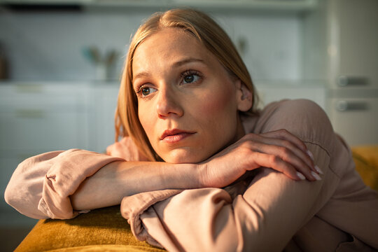 Pensive young woman resting on sofa at home