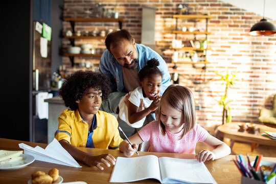Father helping children with homework at kitchen table