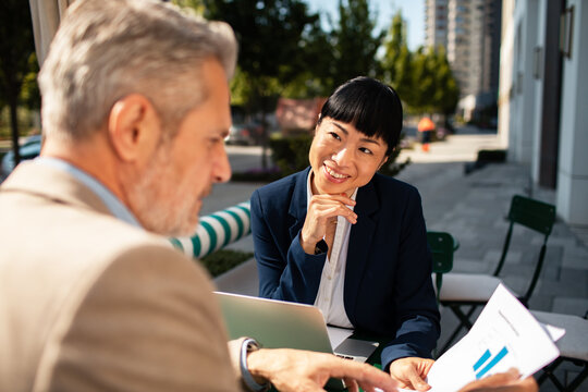 Business colleagues discussing financial report at outdoor cafe