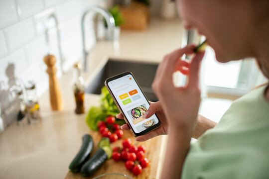 Woman using recipe app while cooking in home kitchen