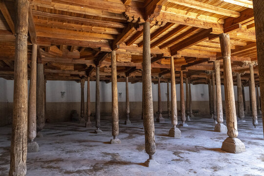 Visitors explore the interior of Juma Mosque in Khiva with wooden columns highlighting its structure