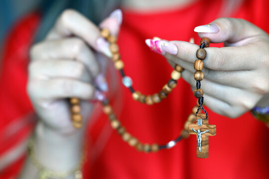 Young girl prays with Rosary while showing care for her nails in Vietnam