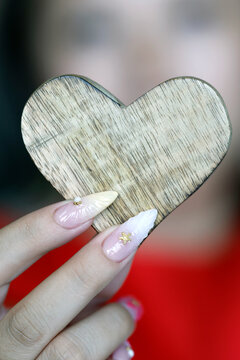 Young girl holds a wooden heart in her hands to express love and faith