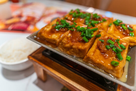 Pan fried tofu served with sauce on a plate with garnishments in a traditional setting on Hong Kong Island