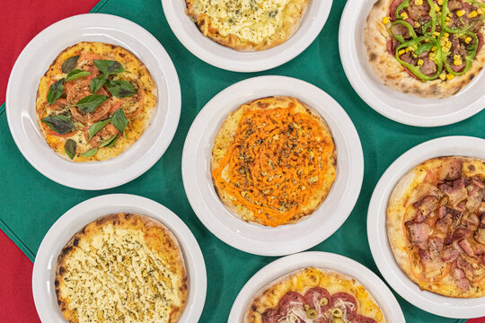 Overhead view of various brazilian pizzas on plates