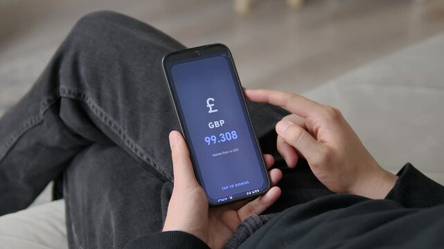 A smartphone screen shows the live market rate for the British Pound against the US Dollar. The simple interface allows users to monitor currency fluctuations with ease