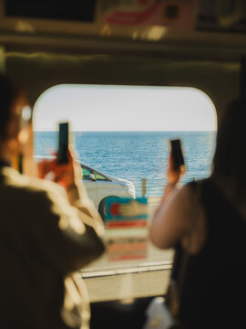 Unrecognisable people photograph sea with smartphone from the train 