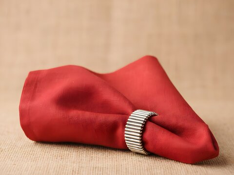 Red napkin with silver ring for elegant table setting and dining decoration, simple background