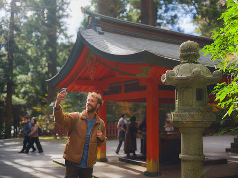 Man takes a selfie with smartphone in Japanese park  