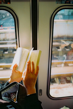Person holding a book during commute by train 