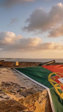 Vertical video: Panning cam filming Portugal flag waving in breeze on parapet at sunset, copy space