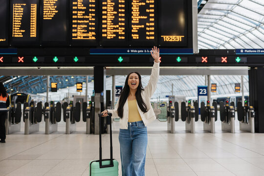 Cheerful traveler waving at railway station platform