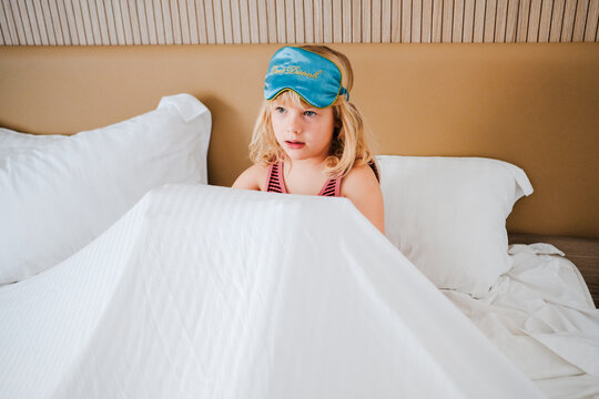 Child in Bed With a Sleep Mask and Blanket During Morning Hours