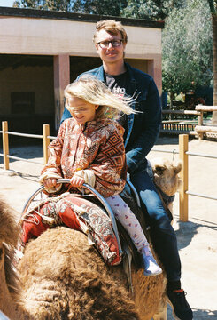 Man and Girl Ride Camel at Zoo in Sunny Day