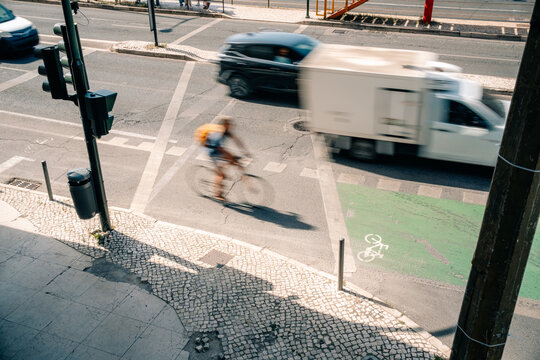 Bicyclist Crosses the Road While Cars Drive Past in the City