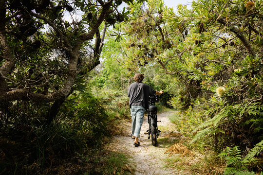 Man pushing e bike through banksia on coastal bush track