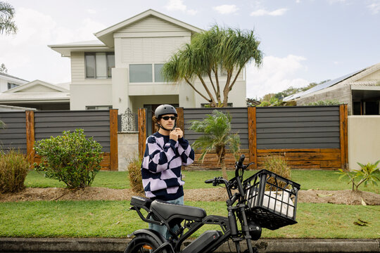 Man fastening helmet on e bike outside coastal beach home