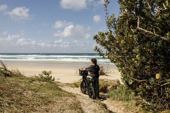 Rider stopping e bike by beach path with ocean view