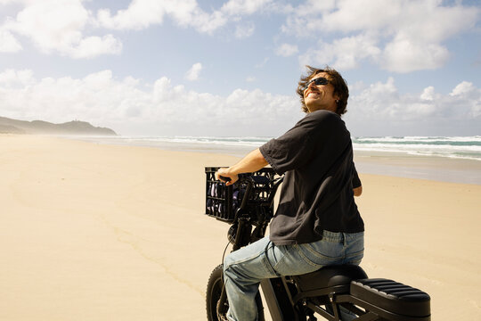Smiling rider on electric bike beside ocean waves in Australia