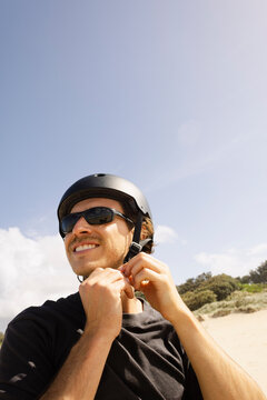 Portrait of a man fastening helmet before riding e bike on sandy beach