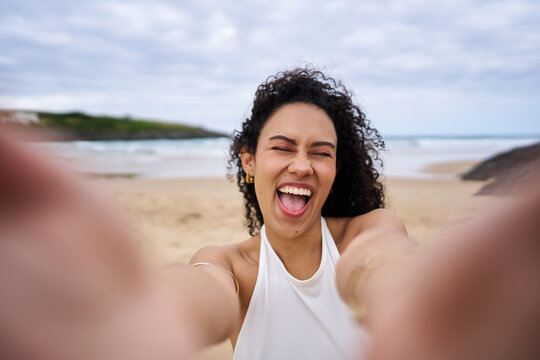 Happy woman capturing selfie on beach enjoying vacation