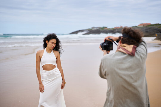 Model posing for a photographer during a beach photoshoot