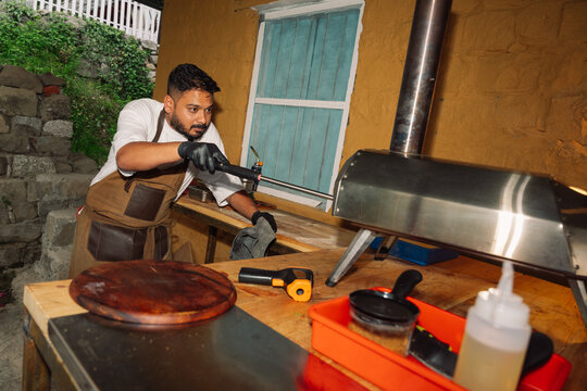 Man Working in an Outdoor Kitchen Preparing Neapolitan Pizza