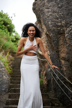 Joyful woman in white dress walking on stone stairs