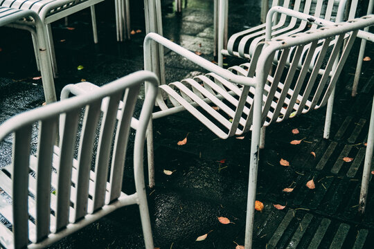 White chairs on wet ground with scattered leaves in outdoor setting