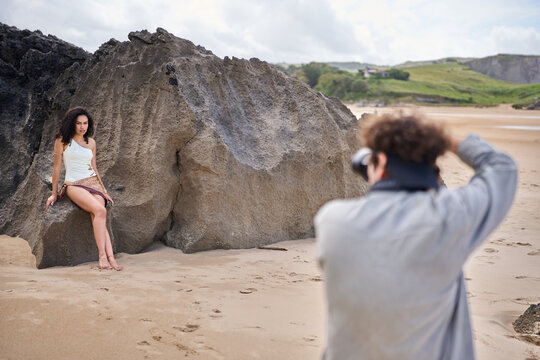 Model posing for a photographer on rocky beach